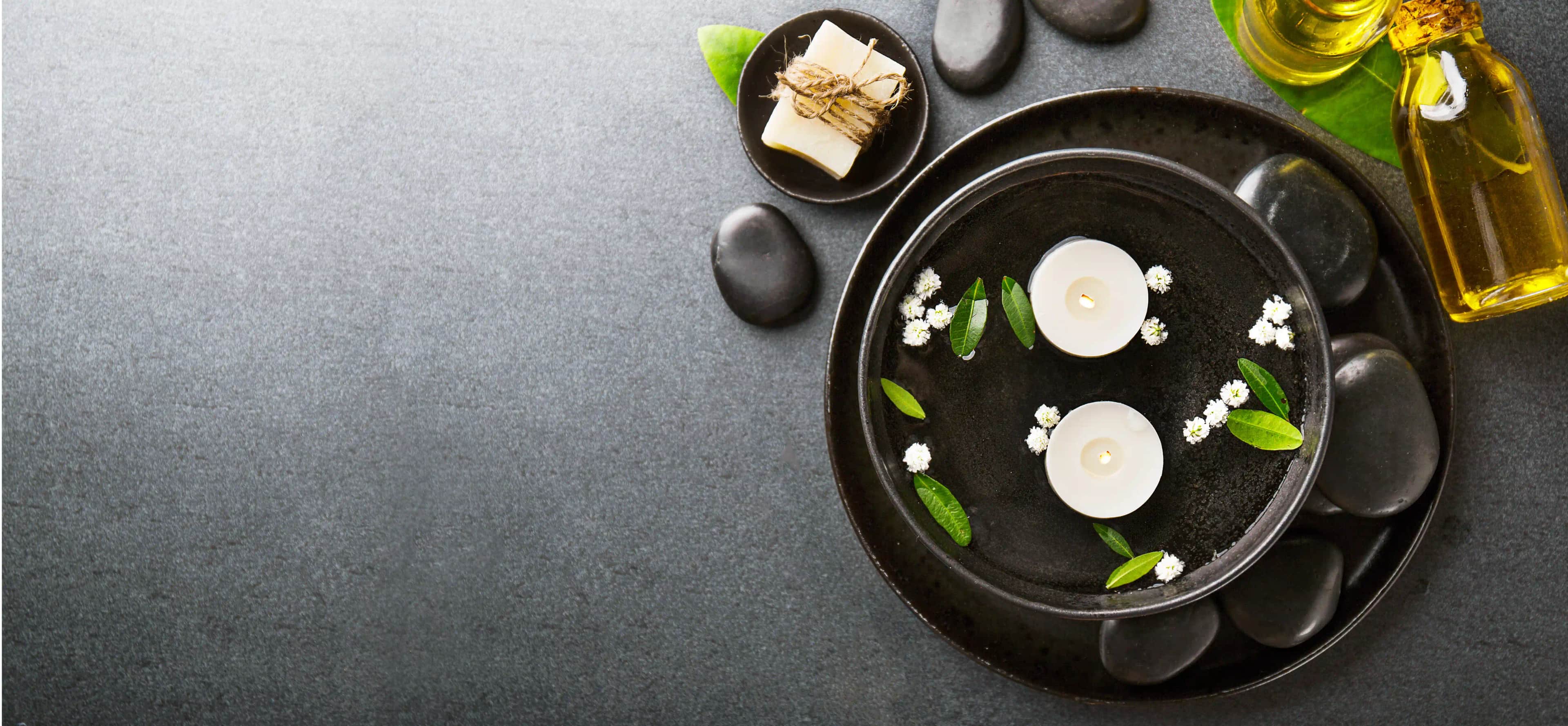 Spa towels, stones and soaps on a dark table